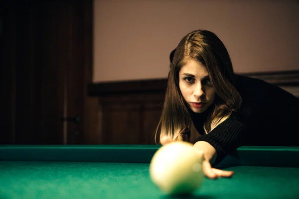 Kadın ışığın altında bilardo oynuyor