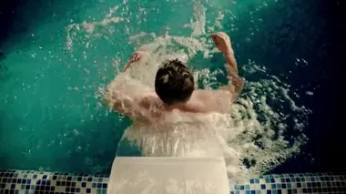 Adam kapalı bir yüzme havuzunda suyun altında yürüyor.