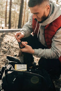 Yakışıklı sakallı adam çam ağacına eğitim ekipmanı yerleştiriyor.