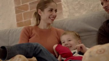 Aile, oğullarını koltukta gıdıklıyor.