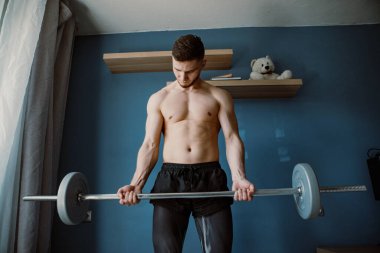 Adam evde halterle egzersiz yapıyor.