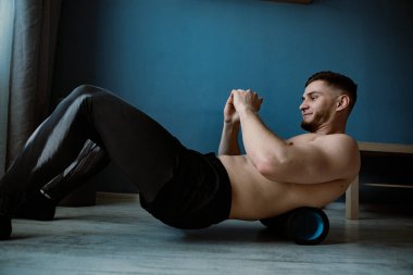 Adam evde silindirle masaj yapıyor.