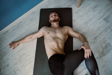 Sakallı kaslı adam evde geriniyor.