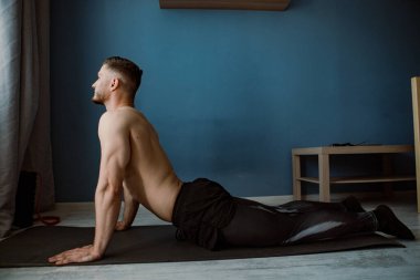 Sakallı kaslı adam evde geriniyor.