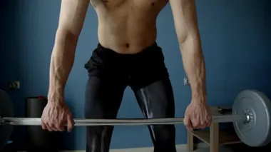 Oturma odasında halterle egzersiz yapan adam.