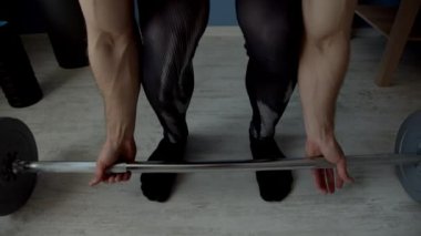 Oturma odasında halterle egzersiz yapan adam.