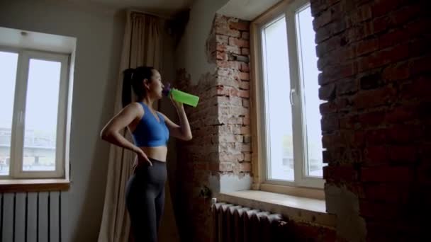 Asiatisk Flicka Sport Kostym Dricka Vatten Nära Fönstret — Stockvideo