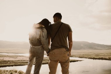 Gün batımında vadide uçurumun kenarında ırklar arası bir çift. 