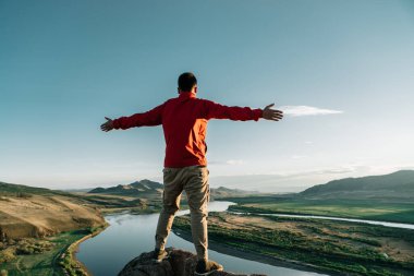 Özgürlüğü gün batımında kayanın tepesinde hisseden bir adam.