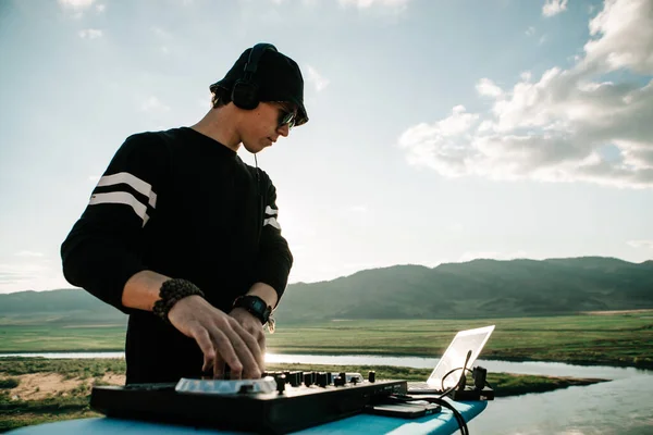 Panama giyen DJ dışarıda müzik çalıyor.
