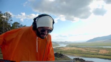 Sakallı DJ dışarıda müzik çalıyor.