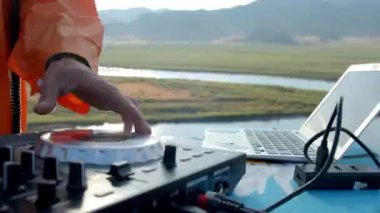 Renkli giysiler içinde DJ dışarıda müzik çalıyor.