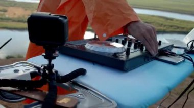 Renkli giysiler içinde DJ dışarıda müzik çalıyor.