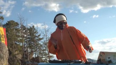 Renkli giysiler içinde DJ dışarıda müzik çalıyor.