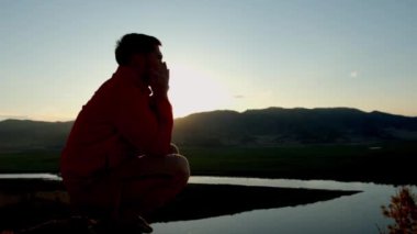 Adam dışarıda günbatımında ulusal bir müzik aleti çalıyor.