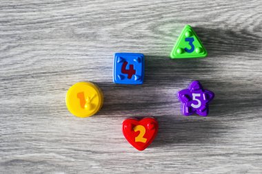 Sayılarla ahşap arka plan üzerinde renkli plastik şekiller