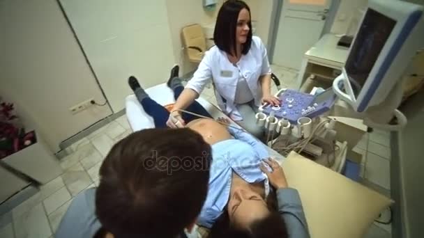 Беременная женщина и муж смотрят на ультразвуковое сканирование ребенка — стоковое видео