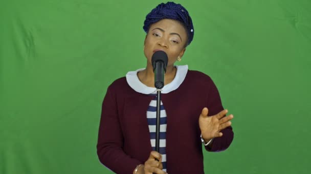 Πορτρέτο του μια όμορφη νεαρή γυναίκα αφρικανική, τραγουδώντας σε πράσινο φόντο. — Αρχείο Βίντεο