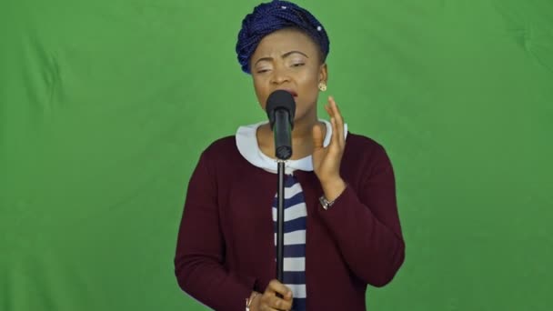 Porträt einer schönen jungen Afrikanerin, die vor grünem Hintergrund singt. — Stockvideo