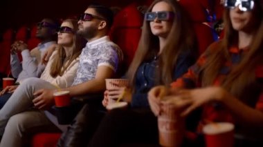 Arkadaşlar sinemada 3d gözlük etkileyici bir film izlerken, kola içme ve patlamış mısır yemek.