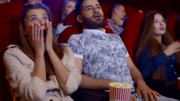 Joven pareja asustada en el cine viendo una película de terror y gritando . — Vídeo de stock