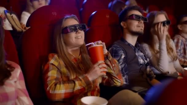 Los jóvenes ven películas en el cine, ven una comedia en 3D, todos sonriendo y comiendo palomitas de maíz . — Vídeo de stock