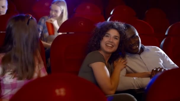 African boy with his girlfriend watching funny movie at the cinema. — Stock Video