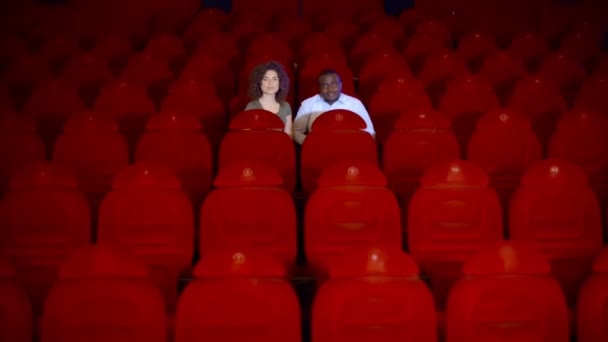 Две влюбленные в большом пустом зале кинотеатра с красными стульями . — стоковое видео