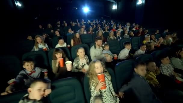 Vue aérienne au cinéma. Enfants regardant dessin animé, manger du maïs soufflé et boire du cola . — Video