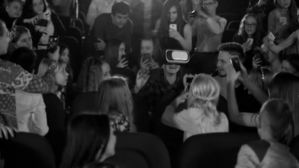 Tajemná dívka v virtuální realita brýle, flash telefon. Děti, které sedí v kině. Černá a bílá metráž. — Stock video