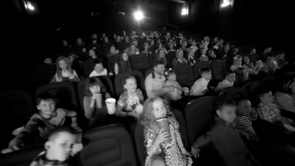 Schwarz-Weiß-Aufnahmen. Videorahmen im Kino mit lustigen Kindern, die Zeichentrickfilme ansehen. — Stockvideo