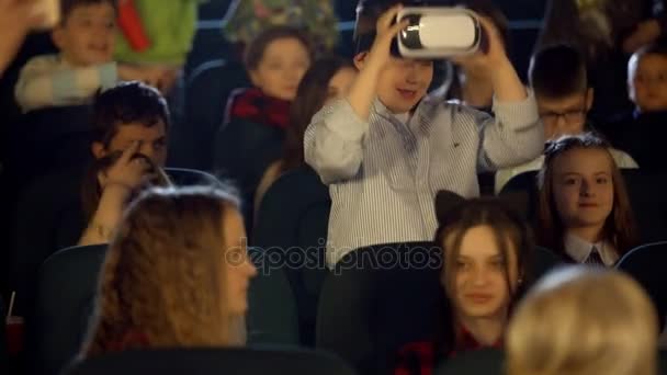 Los niños pequeños en el cine mirando al niño en gafas de realidad virtual . — Vídeos de Stock