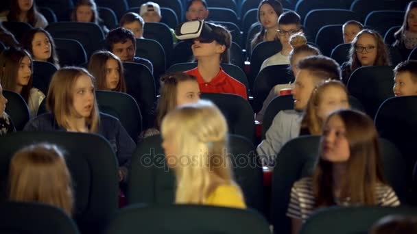Niños pequeños adolescentes en el cine viendo a un niño con gafas de realidad virtual . — Vídeos de Stock