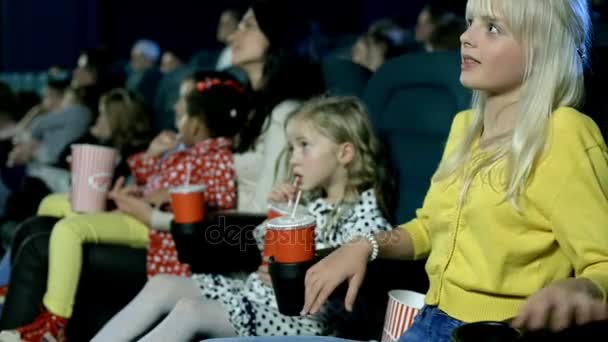 Menina bonita com seus amigos emocionalmente assistindo filme no cinema . — Vídeo de Stock