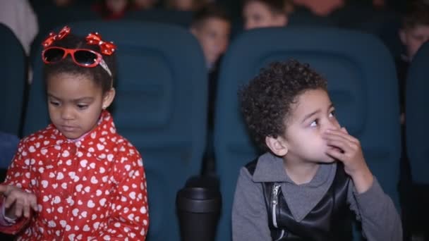 Schöne afrikanische Mädchen und Jungen sitzen in der Halle Kino vor dem Ansehen von Filmen. — Stockvideo