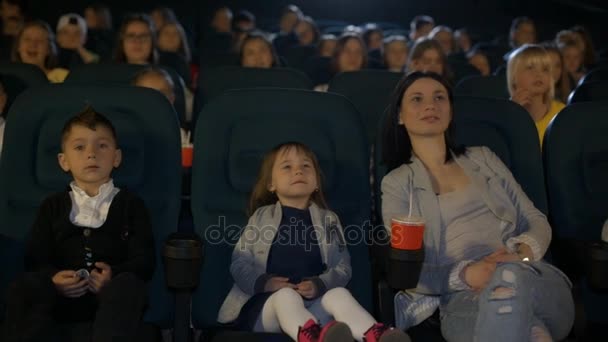 Una mujer viendo una película en un cine con una hija pequeña y amigos . — Vídeos de Stock