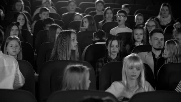 Маленькие девочки и мальчики в кино смотрят на мальчика в очках виртуальной реальности. Черное и белое . — стоковое видео