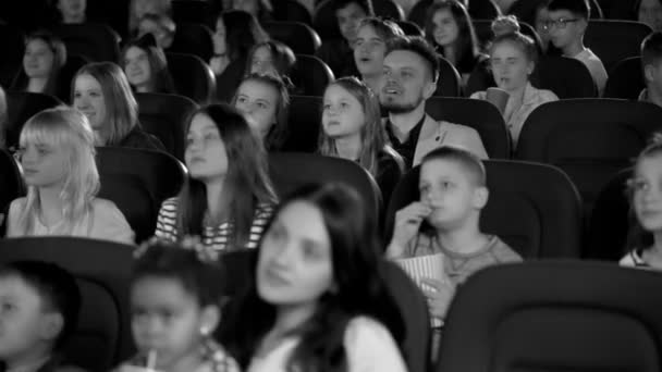 Colpo in bianco e nero. Bambini entusiasti cercando allegro cartone animato nella sala cinema . — Video Stock