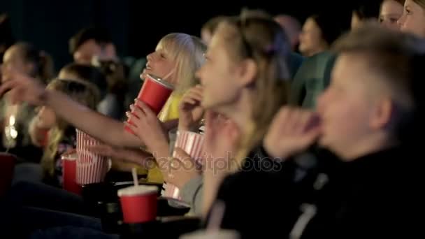 Uśmiechający się trochę dziewczyna oglądając film w kinie, jedzenie popcorn i picie cola, z bliska. — Wideo stockowe