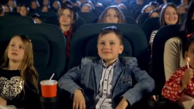 Güzel çocuk ve birçok küçük kız sinemada film izlerken. Portre kadar kapatın.