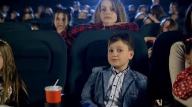 Güzel çocuk ve birçok küçük kız sinemada film izlerken. Portre kadar kapatın.