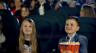 Küçük bir çocuk ve gülümseyen ve coşku ile sinemada bir film izlerken patlamış mısır yemek, kola, içme kız.