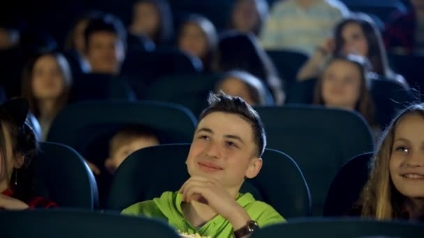 Piękny chłopiec i dziewczynka jedzenie popcorn, picie cola, uśmiechając się i oglądania filmu w kinie z entuzjazmem. — Wideo stockowe