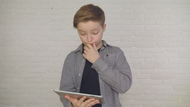 Молодий, задуманий хлопчик використовує технології тачскрін планшетів і читання . — стокове відео