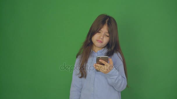 Niña teniendo video chat, videollamada en el teléfono inteligente. Niña saludando y hablando con la cámara del teléfono. Fondo verde. de cerca — Vídeo de stock