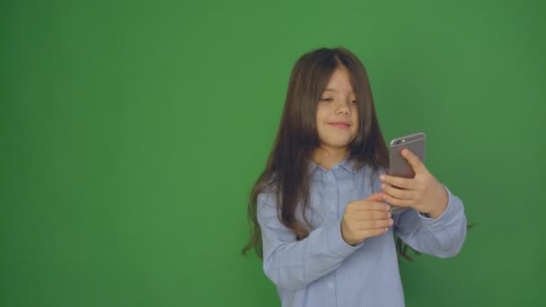 Κοριτσάκι χρησιμοποιώντας smartphone στην οθόνη ένα πράσινο, όμορφο κοριτσάκι λήψης selfie με κινητό τηλέφωνο στο χέρι — Αρχείο Βίντεο