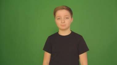 Güzel bir çocuk farklı duygular yeşil bir arka plan üzerinde gösterir. Kamera 4 k.