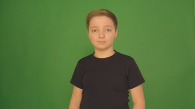 Güzel bir çocuk farklı duygular yeşil bir arka plan üzerinde gösterir. Kamera 4 k.