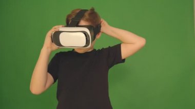 Vr gözlüklü çocuk. closeup çekim. Çocuk duygusal olarak sanal gözlüklere benziyor. Yeşil arka plandaki çocuk. 4k kamera.