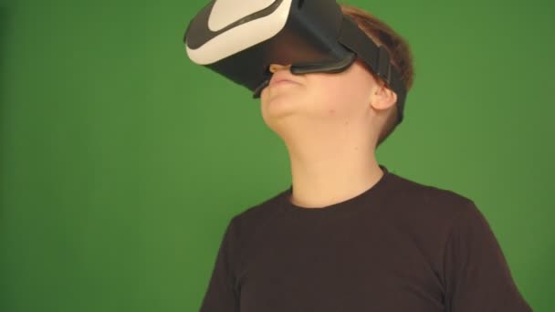 Niedlichen kleinen Jungen gestikuliert glücklich mit vr Virtual-Reality-360-Grad-Brille. Junge vor grünem Hintergrund. — Stockvideo